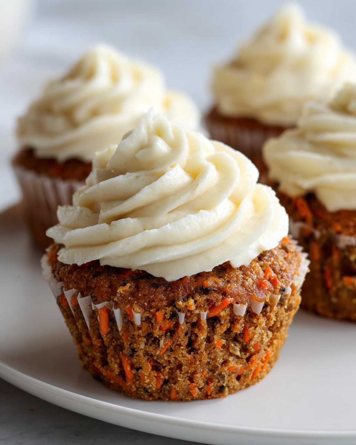 Close-up of a moist Gluten-Free Carrot Cake Cupcakes topped with a swirl of cream cheese frosting.