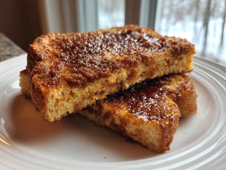 Two slices of thick Gluten-Free Cinnamon Crunch French Toast stacked on a white plate.