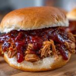 Close-up of a juicy Instant Pot BBQ Pulled Chicken Sandwich piled high with shredded chicken and thick BBQ sauce on a soft bun.