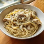 Close-up of Instant Pot Creamy Chicken Alfredo Pasta topped with grated Parmesan and dried herbs.