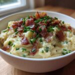 A white bowl filled with Instant Pot Creamy Potato Soup with Bacon crumbles and fresh chives.