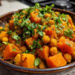 Close-up of vibrant Instant Pot Moroccan Chickpea Stew with large chunks of sweet potato and chickpeas, topped with fresh cilantro.