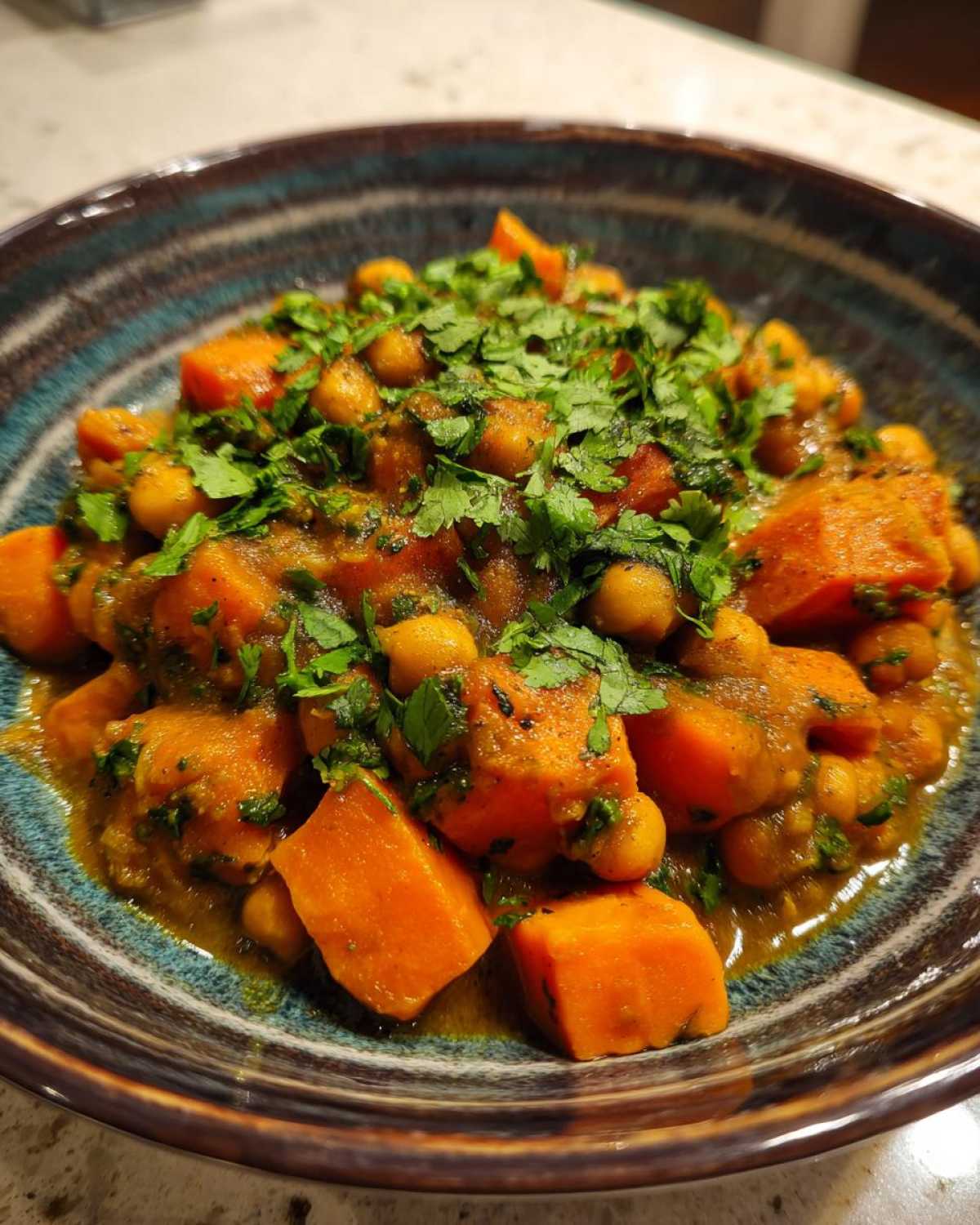 Close-up of Instant Pot Moroccan Chickpea Stew with chunks of sweet potato and chickpeas, topped with fresh cilantro.