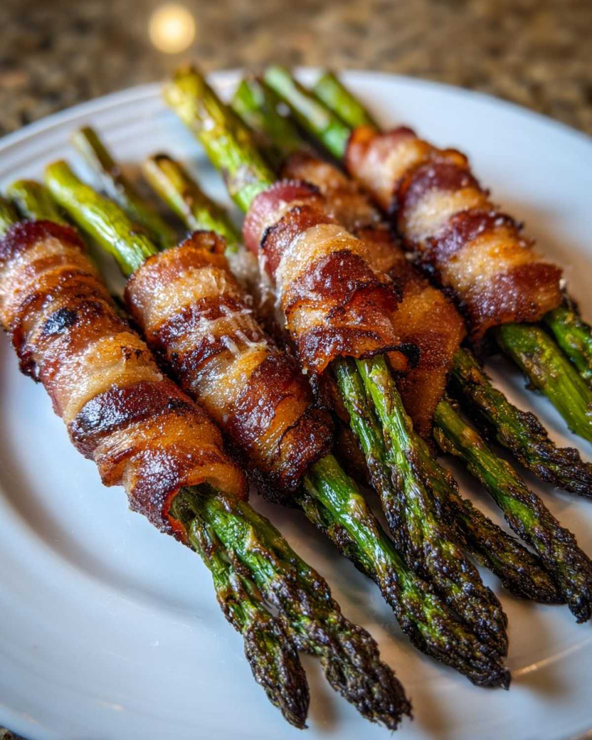 Close-up of perfectly cooked Keto Bacon Wrapped Asparagus Bundles, featuring crispy bacon and bright green asparagus tips.