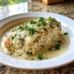 A juicy chicken breast covered in melted cheese and herbs, swimming in a creamy sauce, part of the Keto Creamy Garlic Herb Chicken Bake.