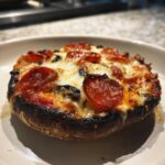 A close-up of a baked Keto Pizza Stuffed Portobello Mushroom topped with melted cheese and pepperoni.