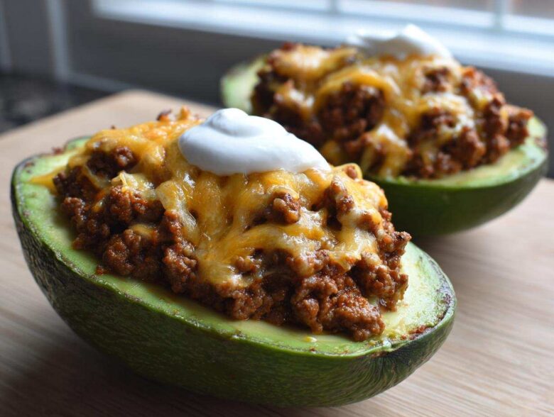 Close-up of Keto Taco Stuffed Avocados filled with seasoned ground meat, melted cheddar cheese, and a dollop of sour cream.