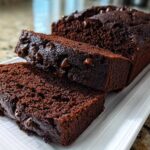 Close-up of moist Gluten-Free Chocolate Zucchini Bread, sliced and topped with melted chocolate chips.