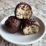 Close-up of No-Bake Chocolate Chip Cookie Dough Truffles dipped in chocolate and sprinkled with mini chips.
