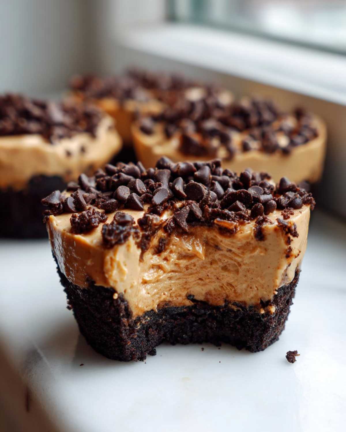 Close-up of a No-Bake Chocolate Peanut Butter Cheesecake Cup with a bite taken out, showing layers.