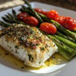 A perfectly cooked fillet of Sheet Pan Lemon Herb Cod with Asparagus and roasted cherry tomatoes.