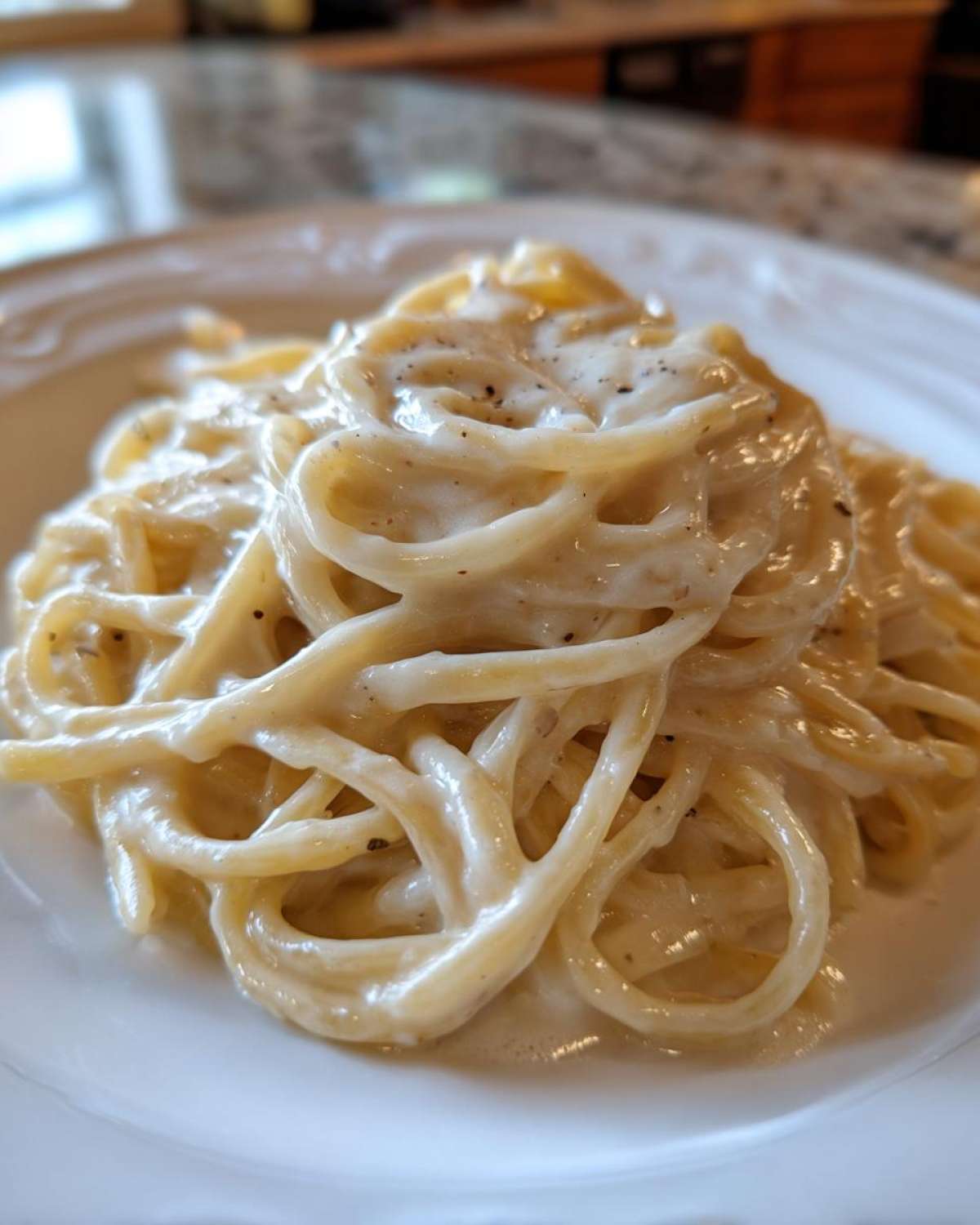 Close-up of spaghetti tossed in rich Vegan Creamy Cashew Alfredo Sauce, topped with cracked black pepper.