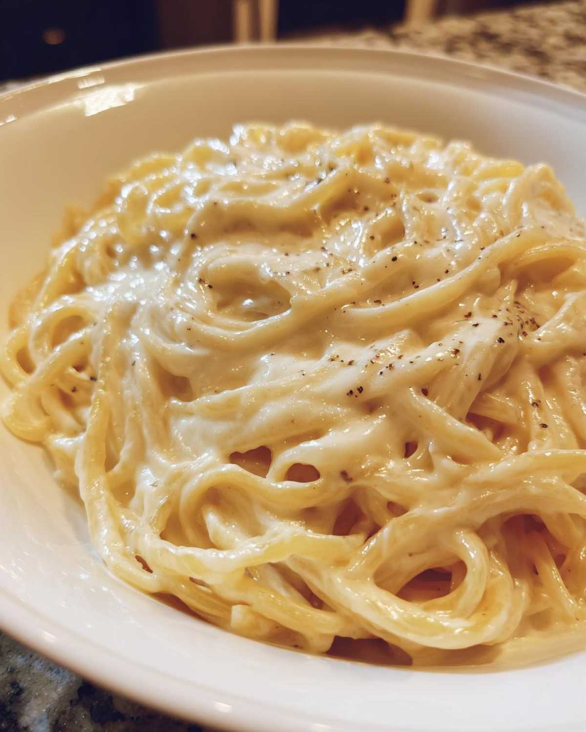 Close-up of spaghetti generously coated in rich Vegan Creamy Cashew Alfredo Sauce and sprinkled with black pepper.