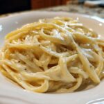 Close-up of fettuccine pasta generously coated in rich Vegan Creamy Cashew Alfredo Sauce, seasoned with pepper.