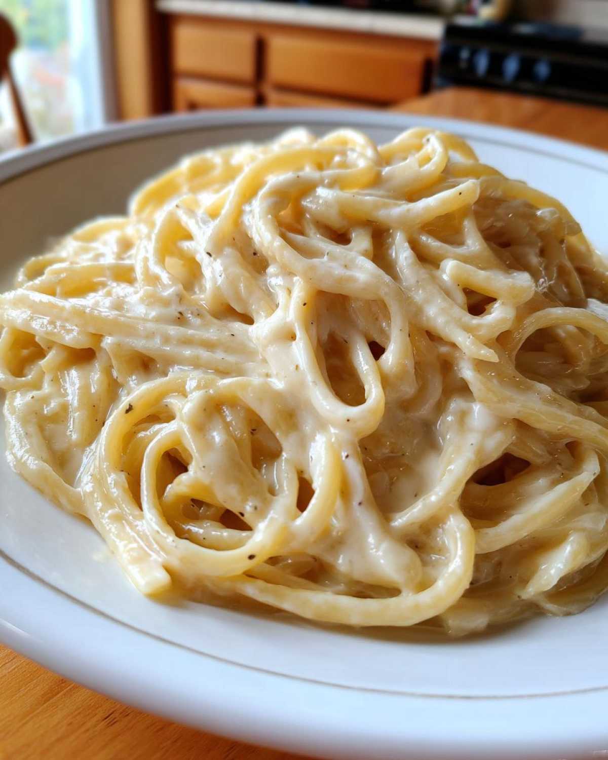 Close-up of fettuccine pasta generously coated in rich Vegan Creamy Cashew Alfredo Sauce, served on a white plate.