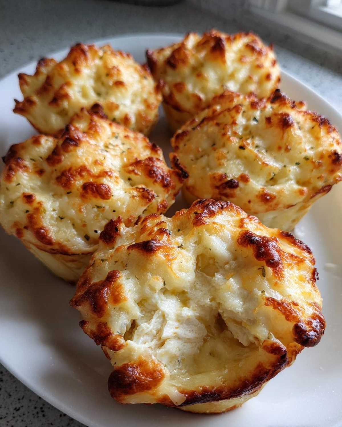 Close-up of baked Cheesy Chicken Alfredo Stuffed Pasta Shells, golden brown and bubbly on top, served on a white plate.