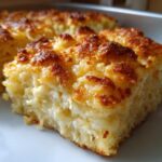 A close-up slice of Cheesy Chicken and Rice Bake showing fluffy rice texture and a deeply browned, golden top crust.