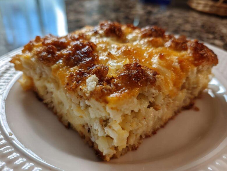 A close-up of a square slice of Cheesy Chicken and Rice Bake showing a creamy interior and a deeply browned, golden top.