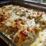 Close-up of baked Cheesy Chicken Stuffed Pasta shells covered in bubbling cream sauce and golden melted cheese.