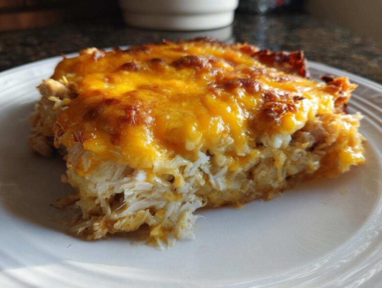 A close-up serving of Cheesy Chicken Tortilla Bake showing shredded chicken and a thick, bubbly layer of melted cheddar cheese.