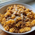 A close-up of Cheesy Ground Beef Pasta Skillet featuring rotini pasta, ground beef sauce, and melted white cheese.