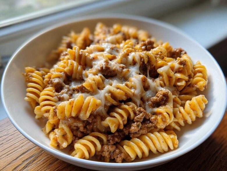 A close-up of Cheesy Ground Beef Pasta Skillet featuring rotini pasta, ground beef sauce, and melted white cheese.