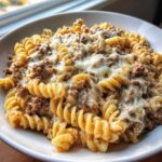 Close-up of Cheesy Ground Beef Pasta Skillet featuring rotini pasta mixed with seasoned ground beef and topped with melted white cheese.