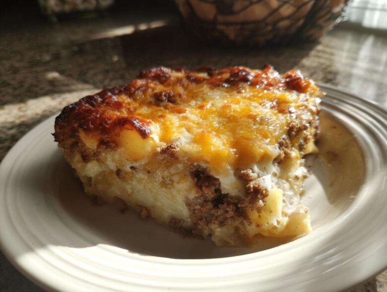 A hearty slice of Cheesy Ground Beef and Potato Bake Comfort Food with a browned, melted cheese topping.