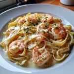 Close-up of delicious Creamy Alfredo Shrimp Pasta with Garlic featuring fettuccine noodles and large pink shrimp, garnished with parsley.
