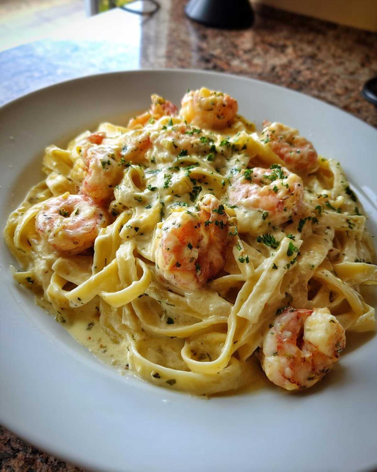 A close-up of fettuccine tossed in rich sauce with plump shrimp, garnished with parsley, showcasing the Creamy Alfredo Shrimp Pasta with Garlic.
