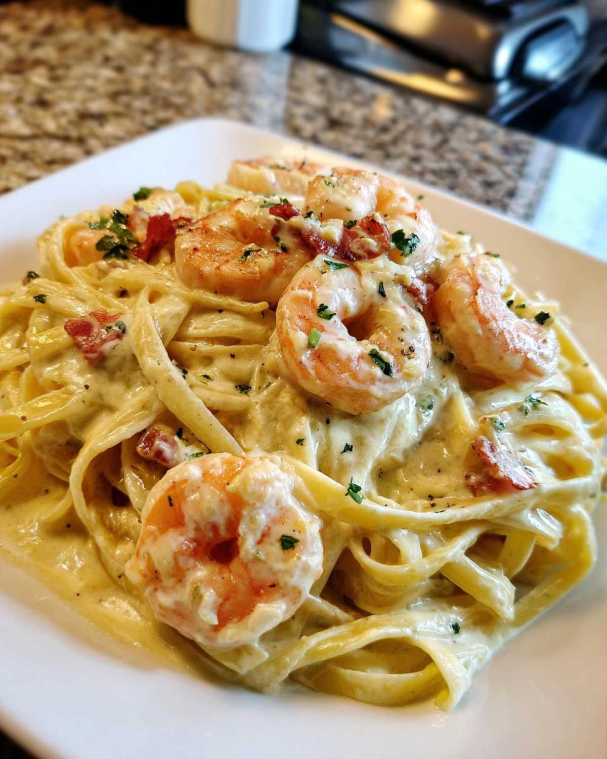 Close-up of Creamy Alfredo Shrimp Pasta with Garlic, featuring fettuccine noodles coated in rich sauce and topped with large shrimp and parsley.
