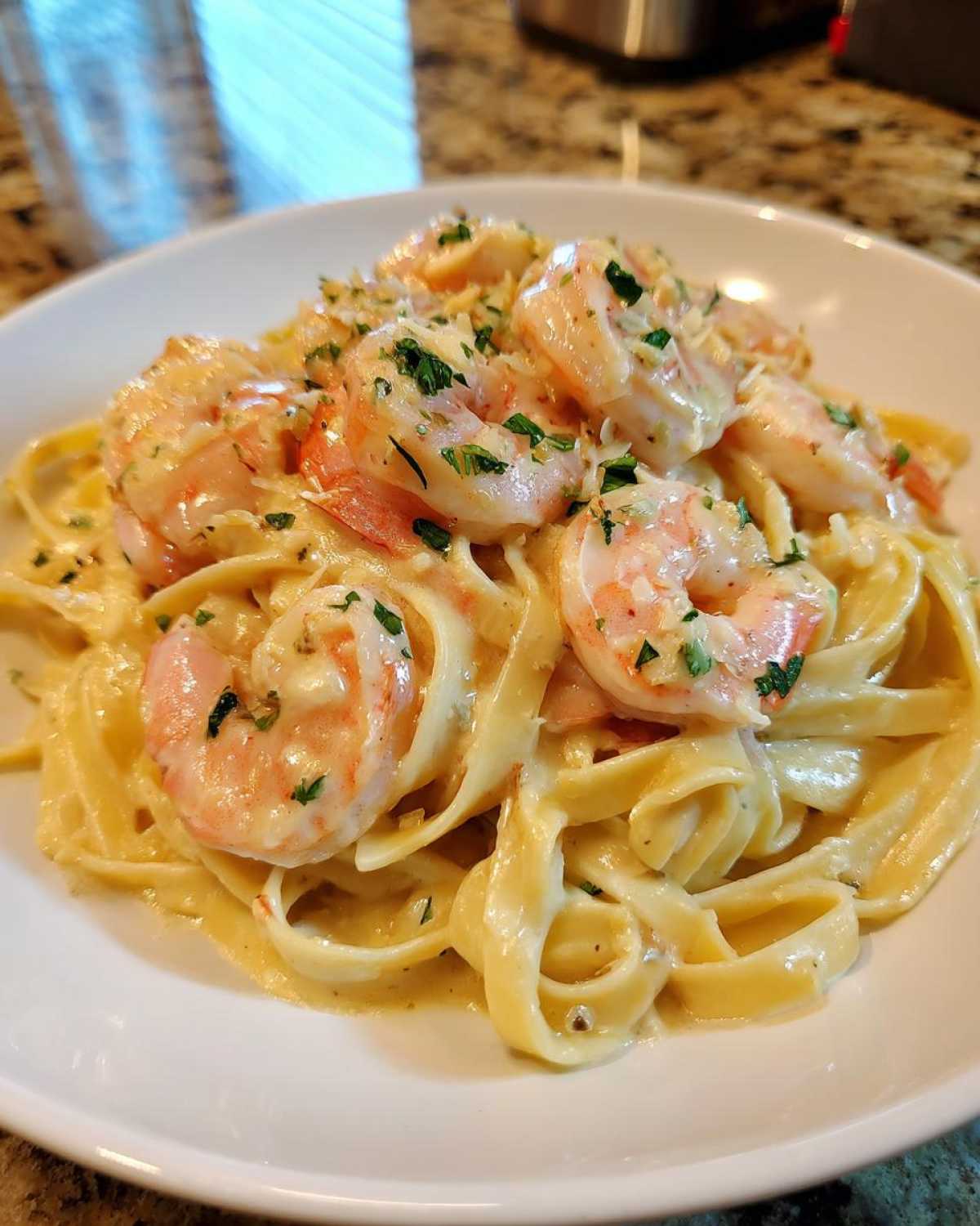 Close-up of Creamy Alfredo Shrimp Pasta with Garlic featuring fettuccine noodles coated in rich sauce and topped with pink shrimp and parsley.