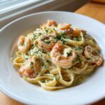 A close-up of rich Garlic Butter Shrimp Alfredo Pasta in a white bowl, topped with fresh parsley.
