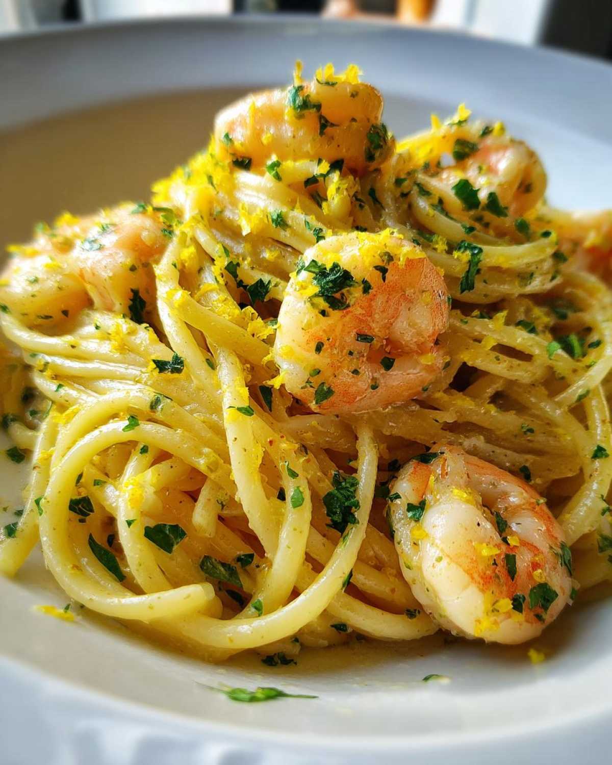 Close-up of a serving of Creamy Lemon Shrimp Pasta, topped generously with lemon zest and parsley.