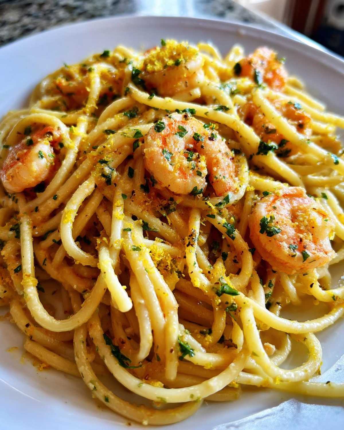 Close-up of Creamy Lemon Shrimp Pasta with Garlic Sauce, featuring thick pasta coated in sauce, topped with shrimp, parsley, and lemon zest.
