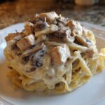 A perfectly plated serving of Creamy Mushroom Chicken Alfredo Pasta featuring fettuccine noodles coated in rich sauce.
