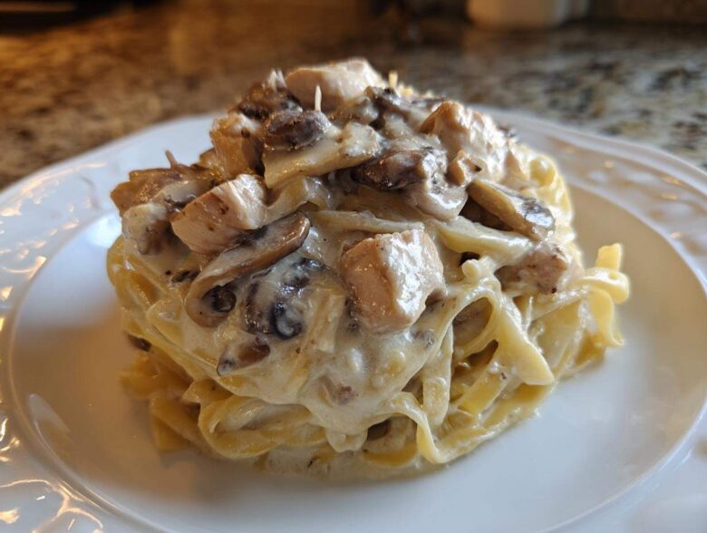 A perfectly plated serving of Creamy Mushroom Chicken Alfredo Pasta featuring fettuccine noodles coated in rich sauce.