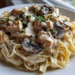 A close-up of a serving of Creamy Mushroom Chicken Pasta with Garlic Sauce, featuring fettuccine, diced chicken, and sliced mushrooms.