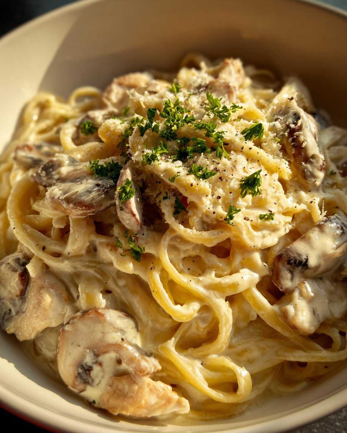 Close-up of Creamy Mushroom Chicken Pasta with Parmesan, topped with grated cheese and fresh parsley.