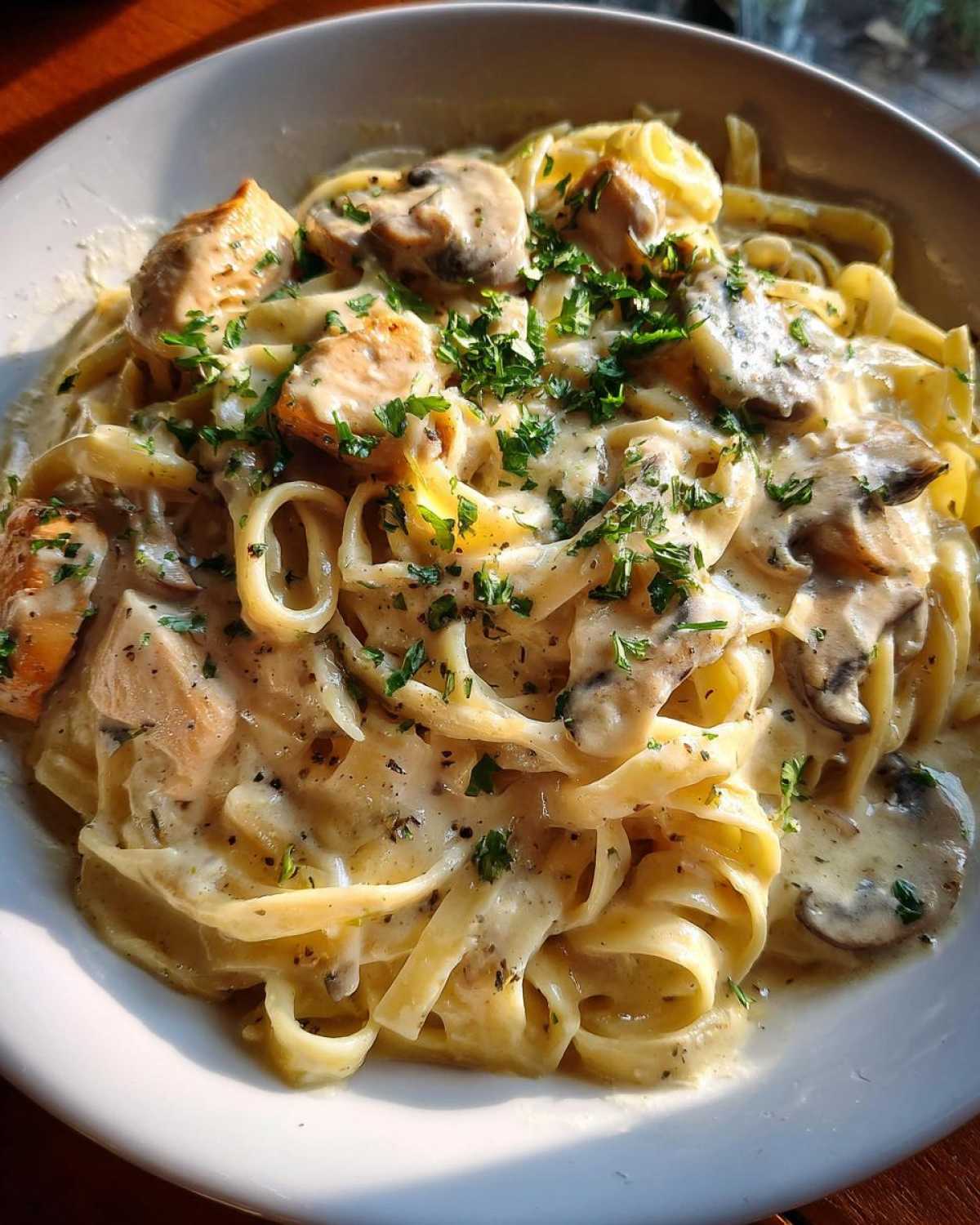 A close-up of rich Creamy Mushroom Chicken Pasta with Parmesan, garnished with fresh parsley.