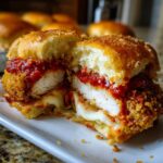 Close-up of Crispy Chicken Parmesan Sliders with Cheese cut in half, showing melted mozzarella and marinara sauce.