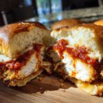 Close-up of a Crispy Chicken Parmesan Slider cut in half showing crispy chicken, melted cheese, and marinara sauce.