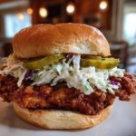 A close-up of a juicy Crispy Chicken Sandwich with Creamy Slaw, pickles, and a brioche bun.
