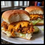 Two Crispy Chicken Sliders with Spicy Mayo dripping over the fried chicken patty, served on soft buns with lettuce.