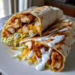 Two halves of a Crispy Chicken Wrap with Ranch Sauce showing crispy chicken, lettuce, and cheese inside.