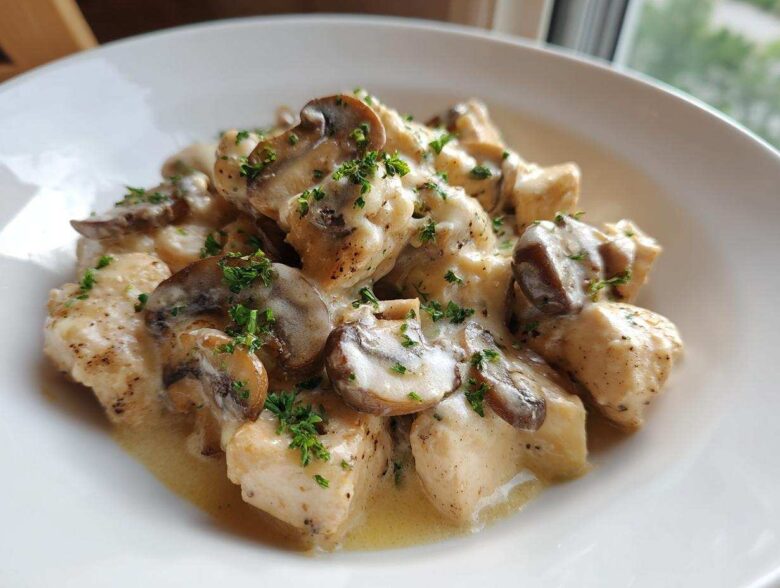 Close-up of tender chicken pieces and sliced mushrooms in a creamy garlic butter sauce, garnished with parsley, from the Garlic Butter Chicken and Mushroom Skillet Dinner.