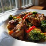 Close-up of glossy Garlic Butter Chicken Bites mixed with vibrant broccoli and red bell peppers.