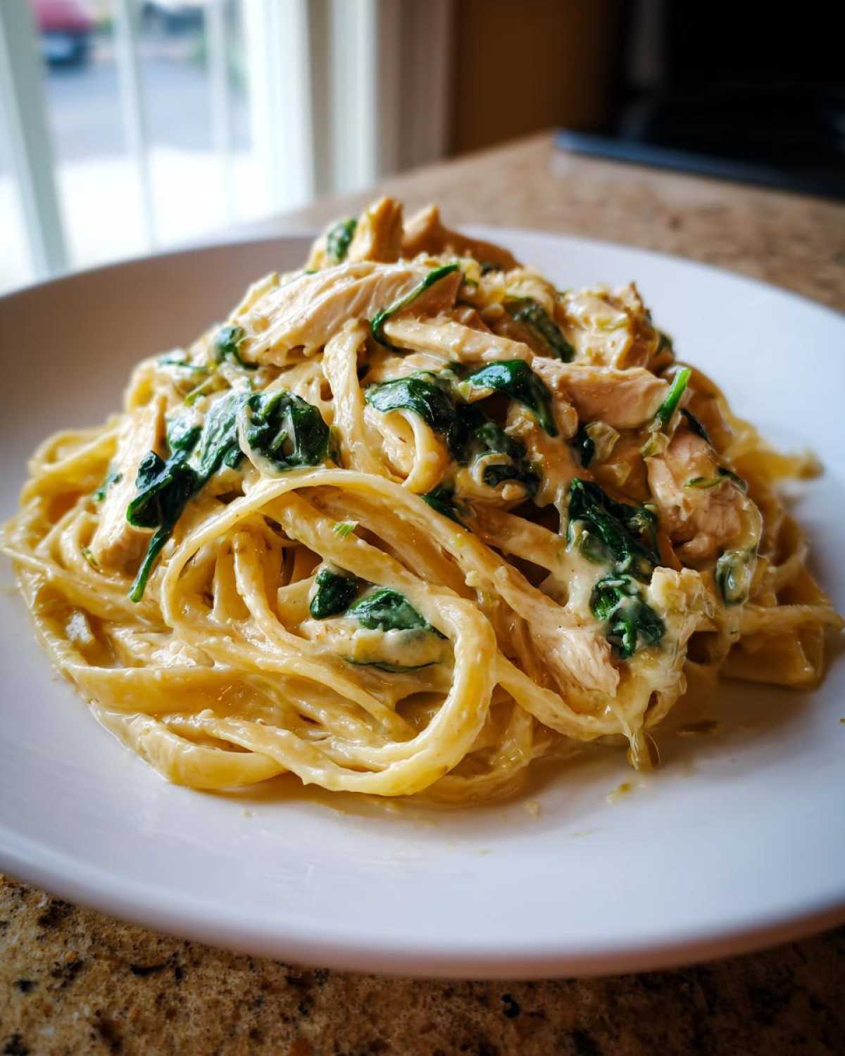 Close-up of creamy Garlic Butter Pasta with Chicken and Spinach served on a white plate.