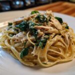 A close-up of a serving of Garlic Butter Pasta with Chicken and Spinach on a white plate.
