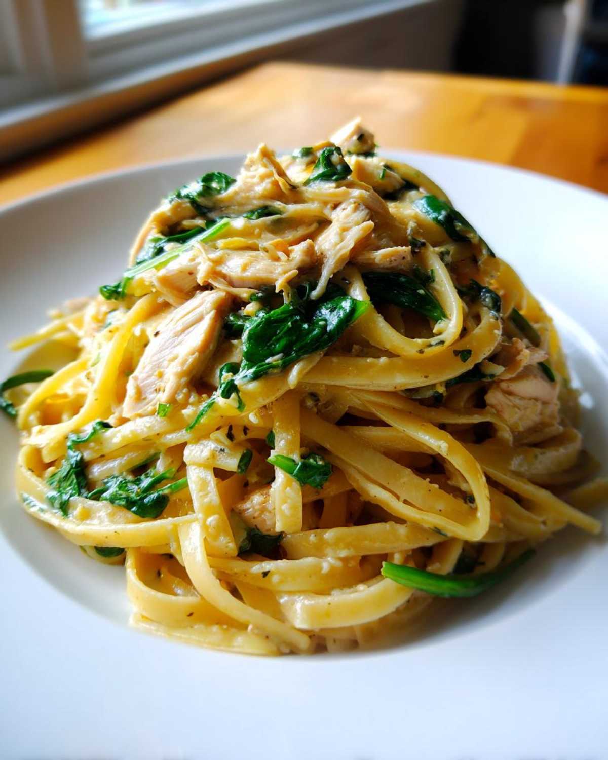 A close-up of a serving of Garlic Butter Pasta with Chicken and Spinach tossed in a creamy sauce.